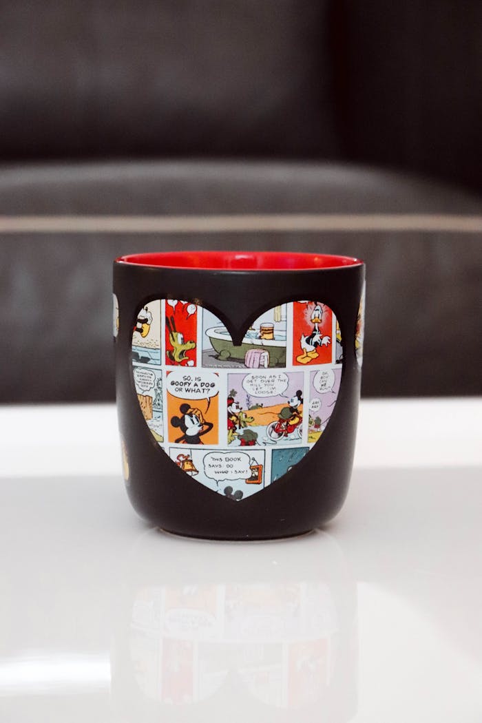 Black mug with a heart-shaped cutout revealing a colorful cartoon comic design, perfect for Valentine
